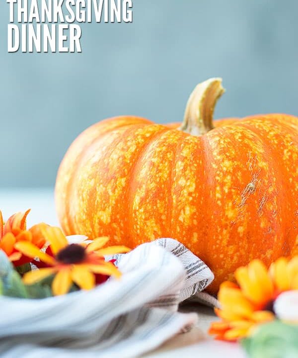 Image of pumpkin and flowers. Learn how to host thanksgiving on a budget. Text overlay reads, "How to Budget for Thanksgiving Dinner"